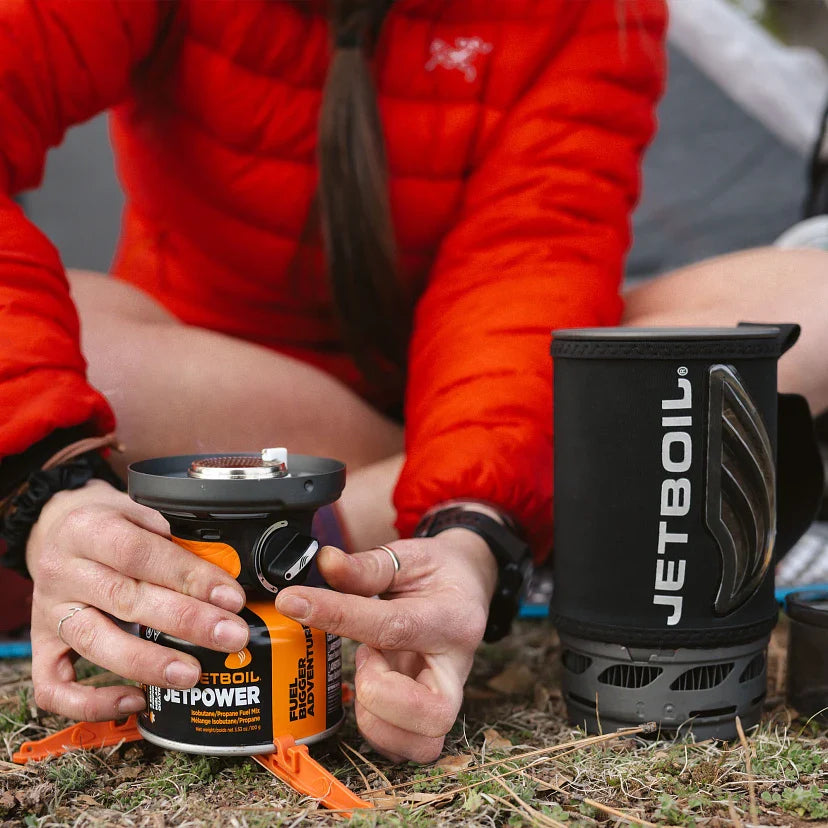 Person in red jacket using a Jetboil stove outdoors