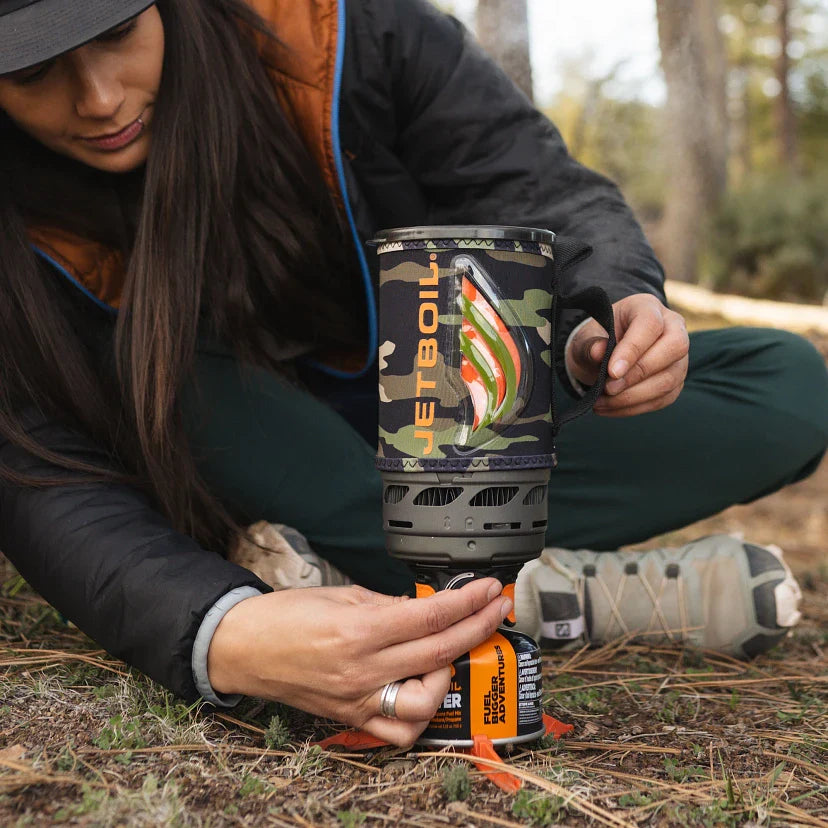 Person holding a Jetboil cooking system in a forest setting