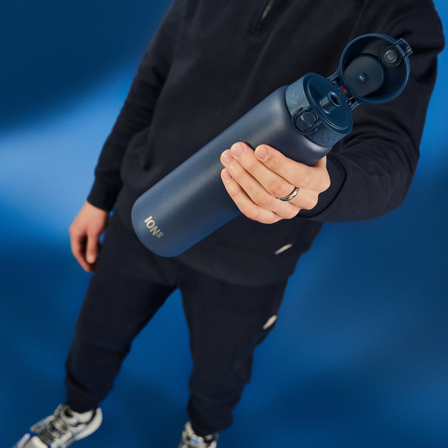 Person holding a blue water bottle with a blue background