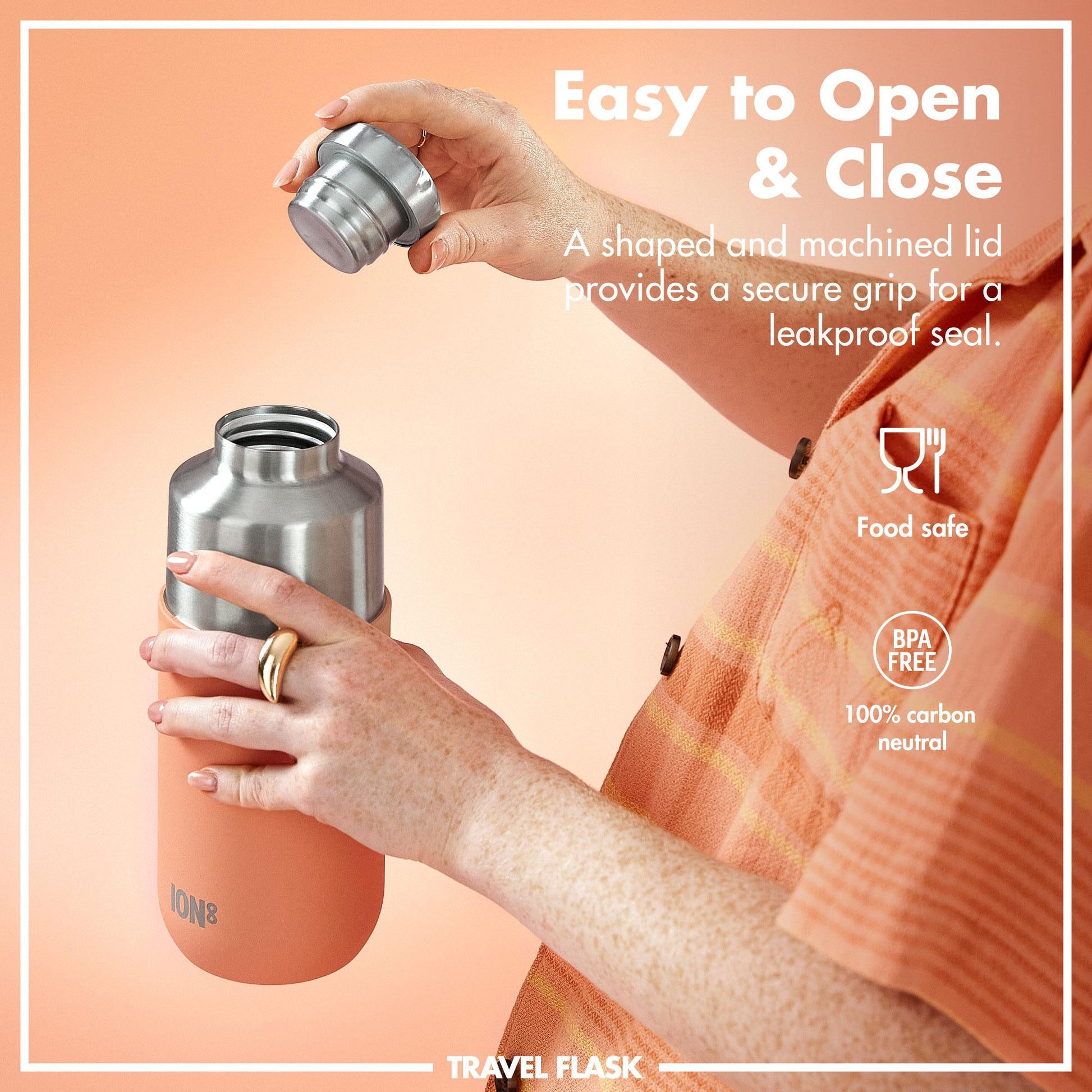 Person holding a travel flask with a shaped and machined lid on an orange background