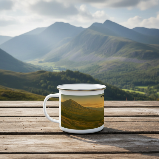 White enamel camping mug with mountain landscape print, set on wooden surface with distant hills.