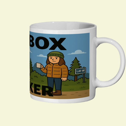 Mug with a graphic design of a person in a parka holding a box labeled 'Box Baker' against a lay-by sign.