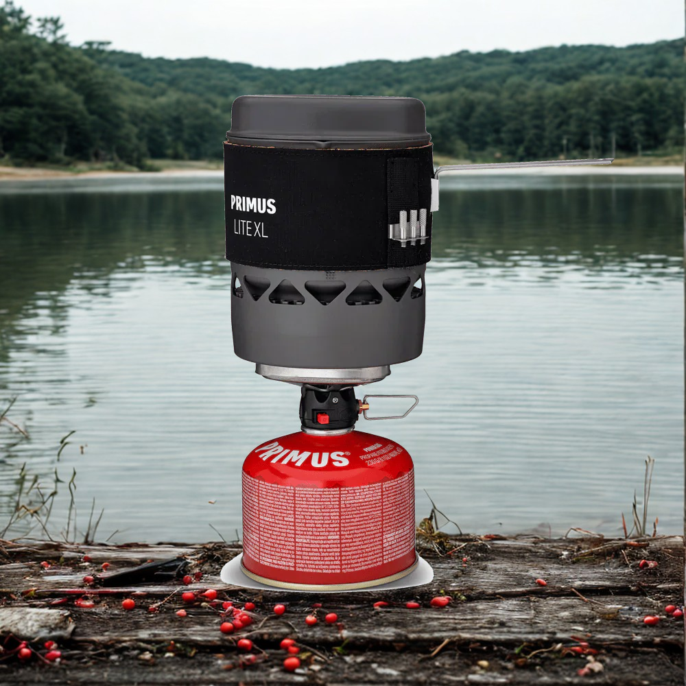 Primus Lite XL camping stove with red fuel canister on a wooden platform by a lake.