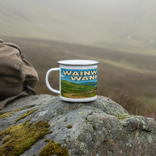 White enamel mug with green and blue Lake District landscape and bold "Wainwright Wanker" text, silver rim.