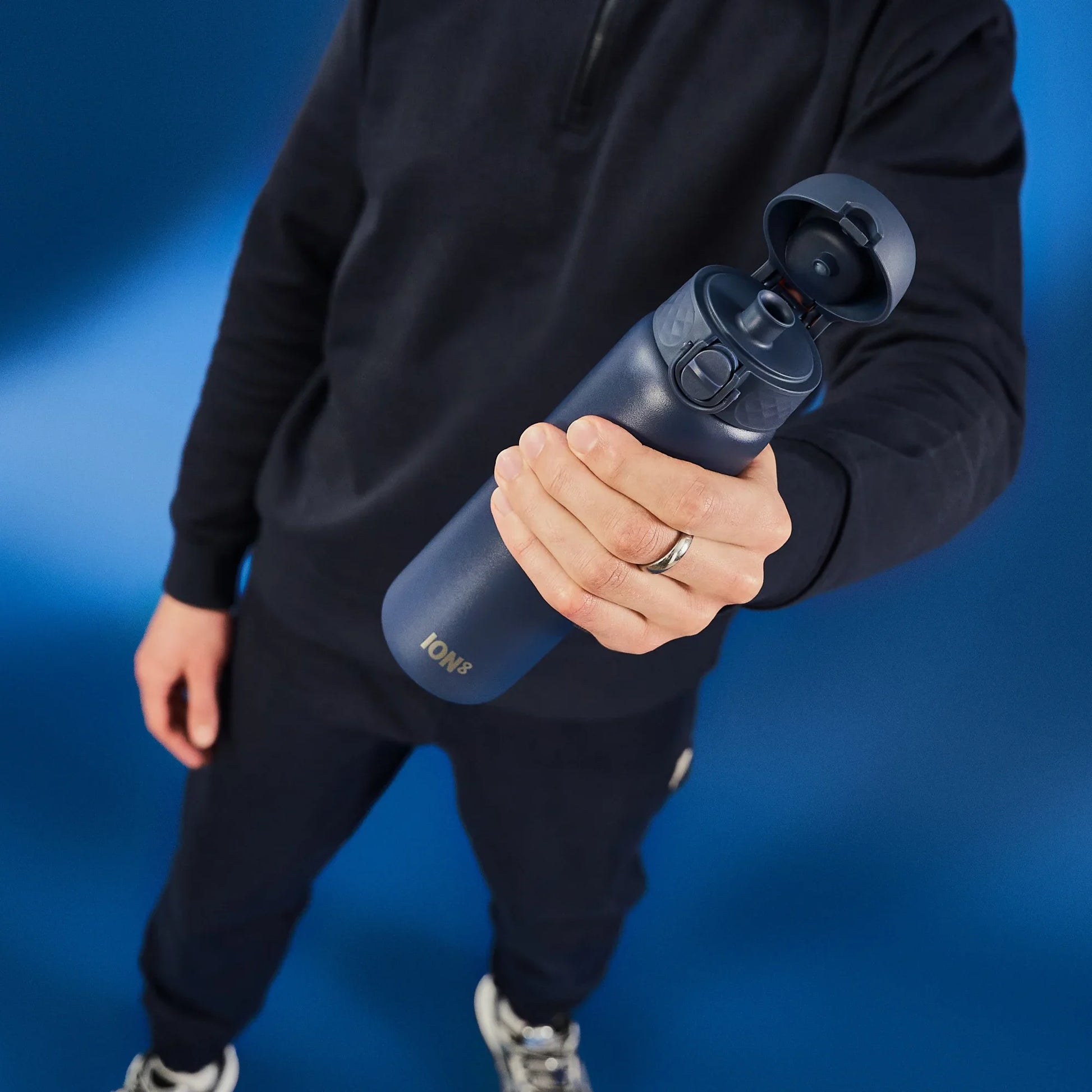 Person holding a blue water bottle against a blue background