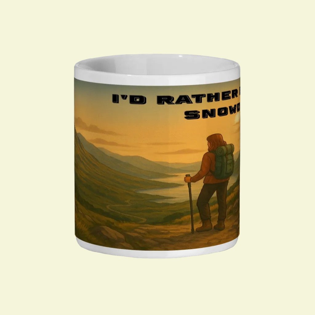 White ceramic mug with sunset mountain hiking scene and "I'd Rather Be in Snowdonia" text.