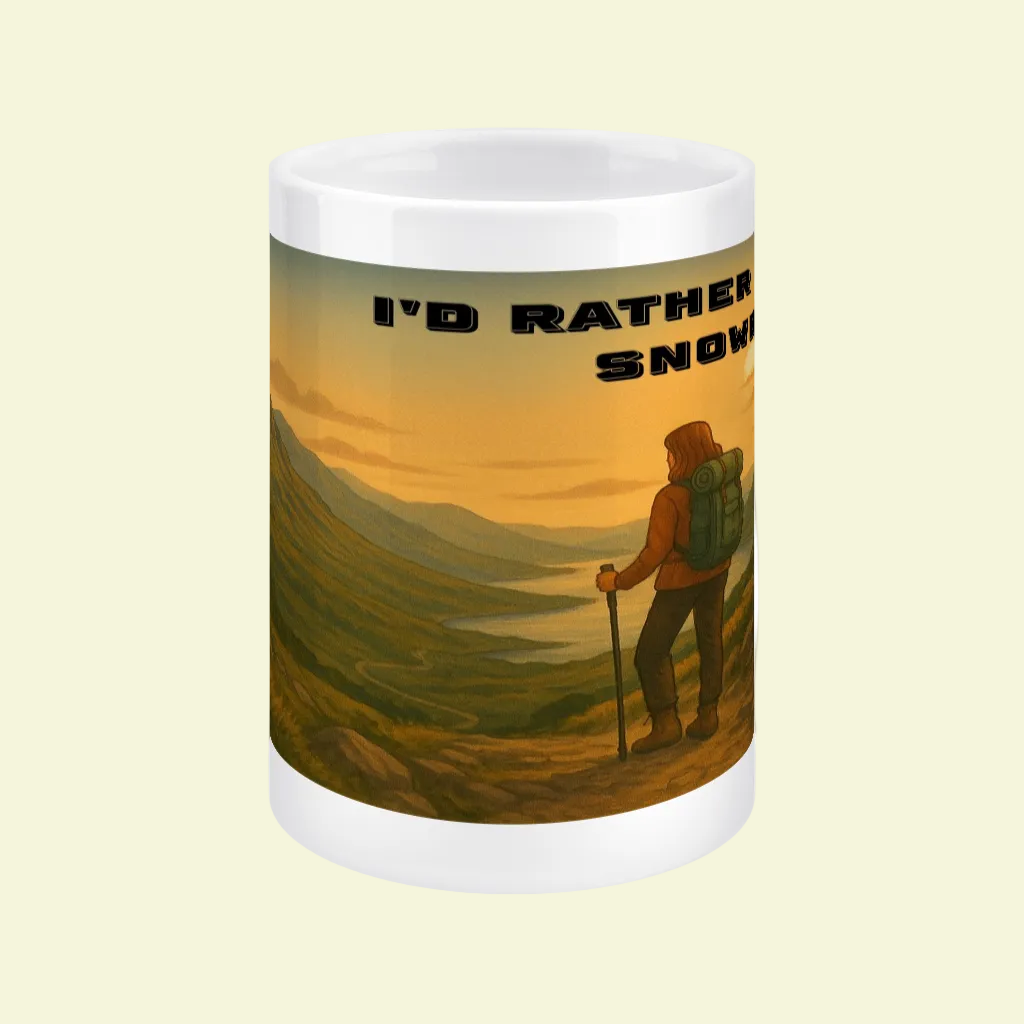 White ceramic mug with hiker overlooking green hills at sunset and text "I'd Rather Be in Snowdonia".