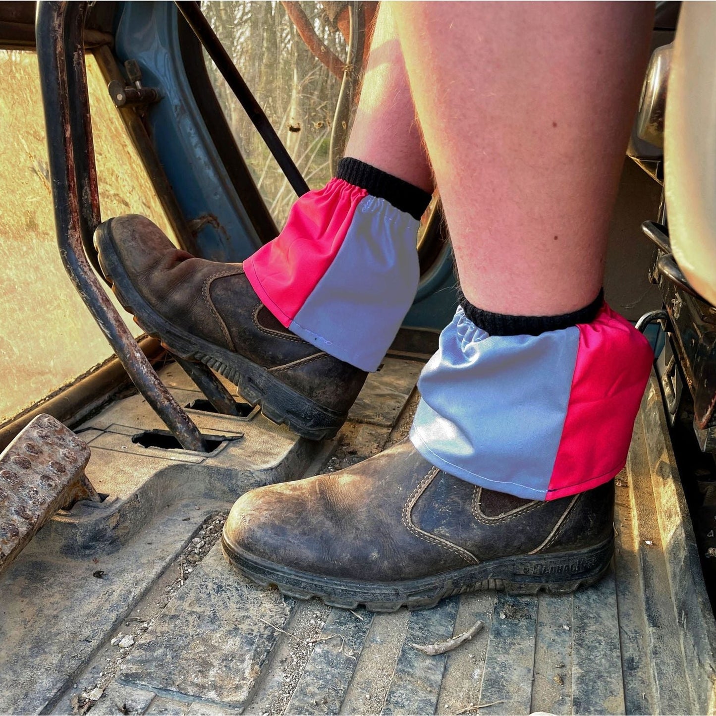 Person wearing work boots with colorful gaiters on a construction site.
