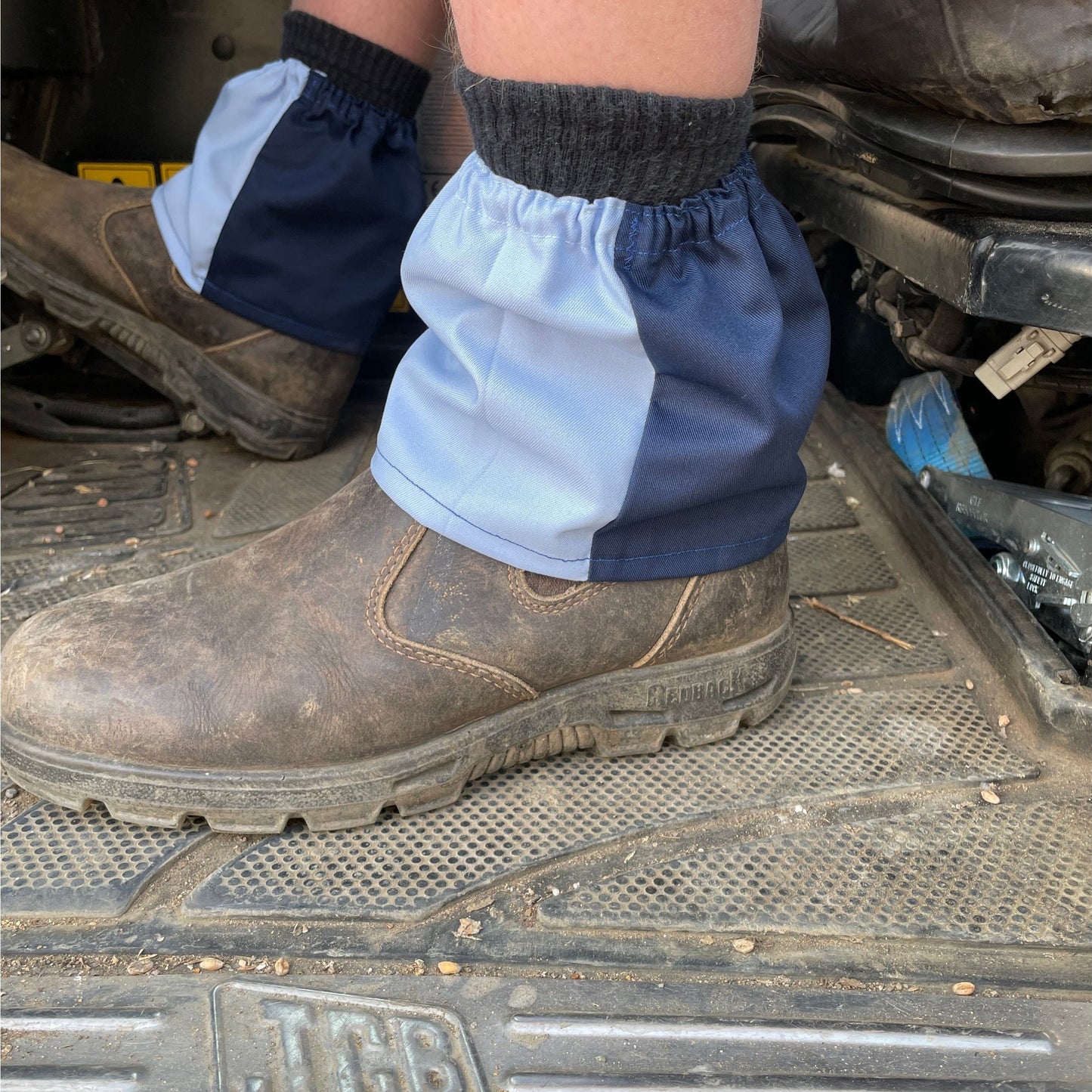 Person wearing blue boot covers over brown work boots on a metal surface.