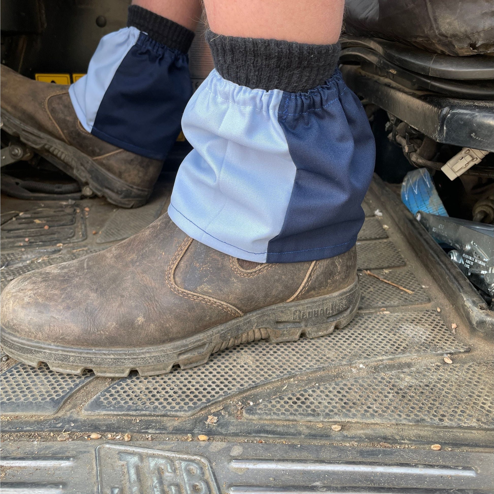 Person wearing blue boot covers over brown work boots on a metal surface.