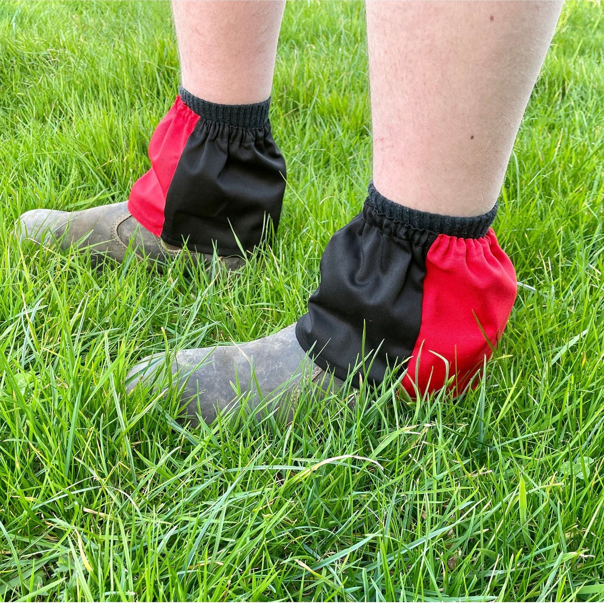 Person wearing black and red ankle covers on grass