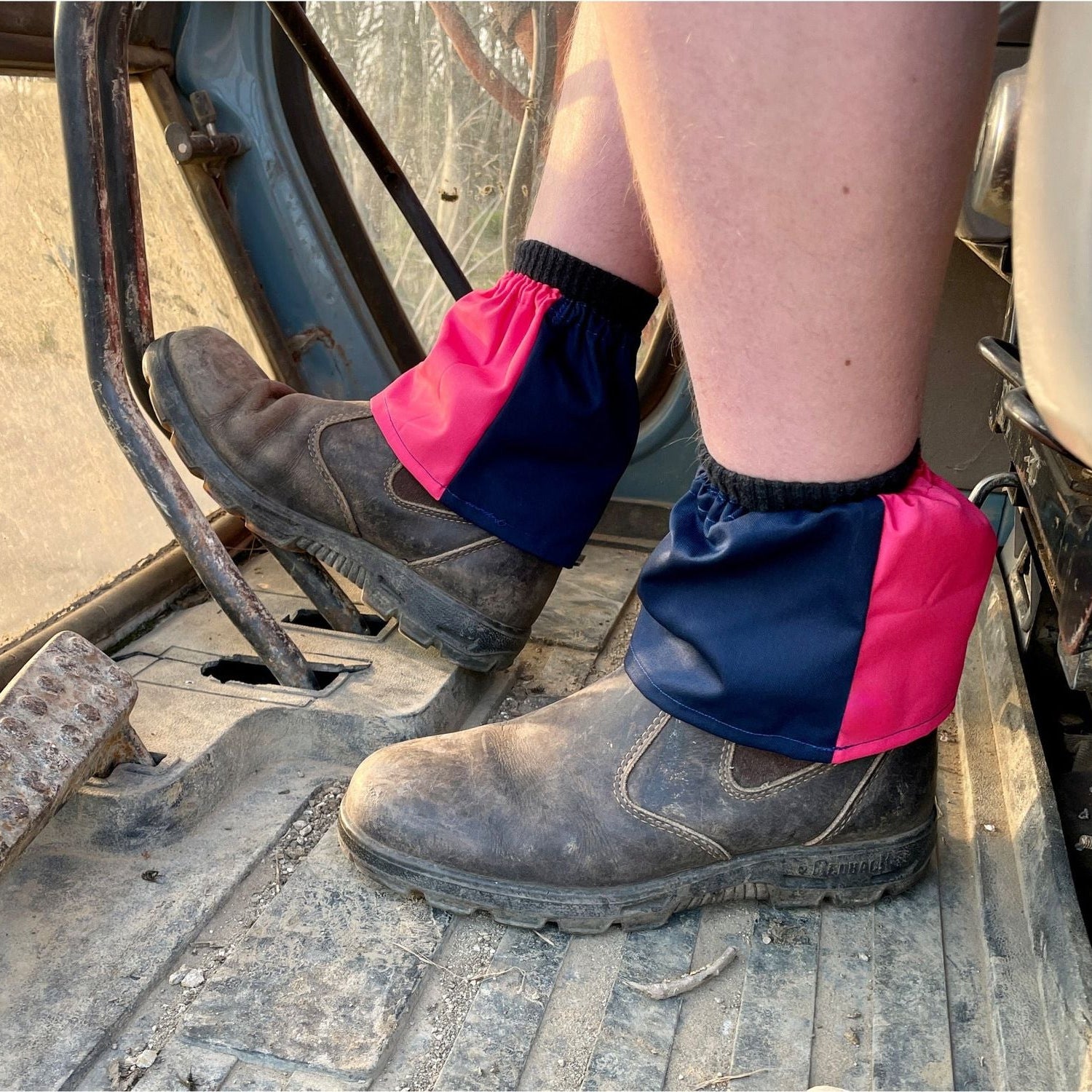 Person wearing pink and blue gaiters on a construction site