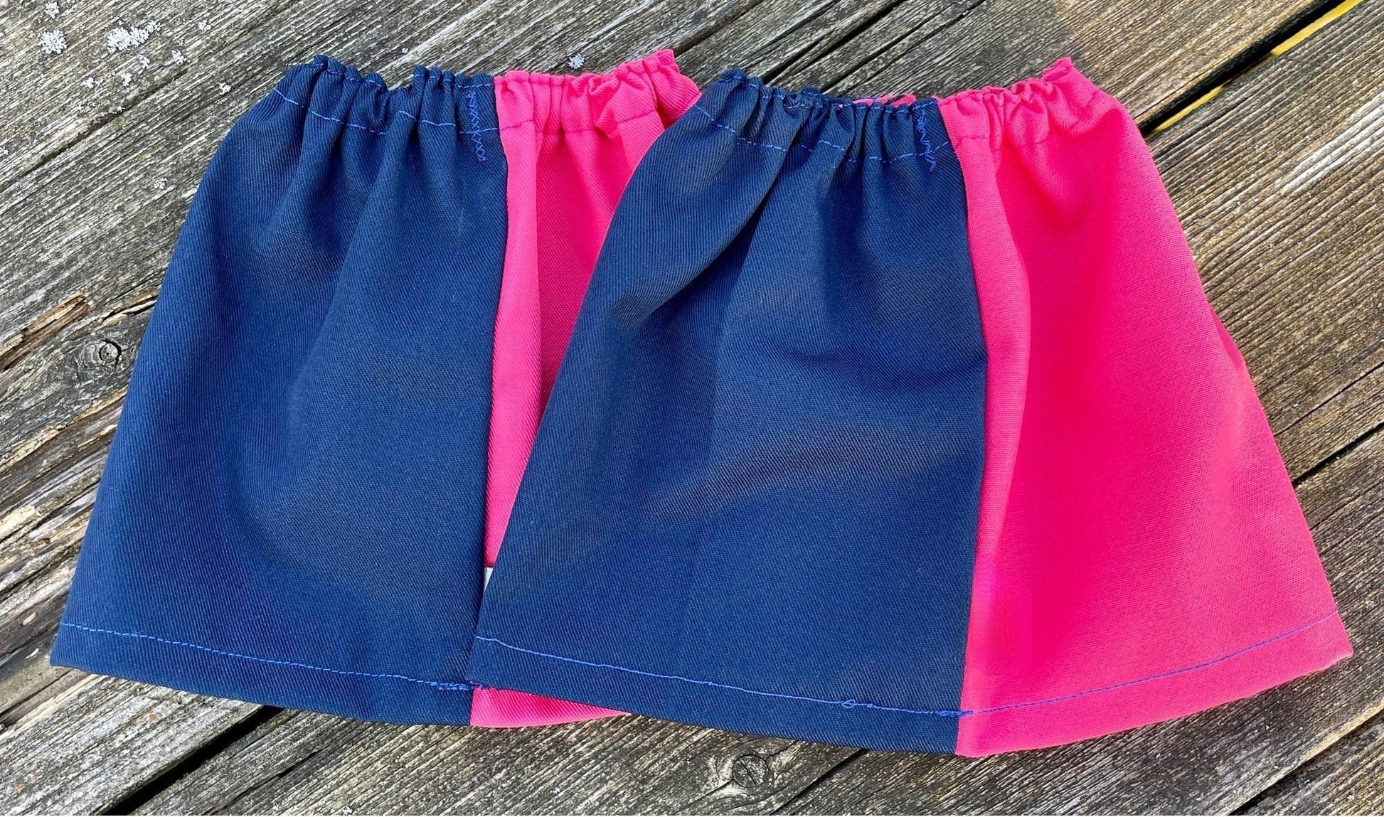 Two colorful gators, one blue and one pink, on a wooden surface.