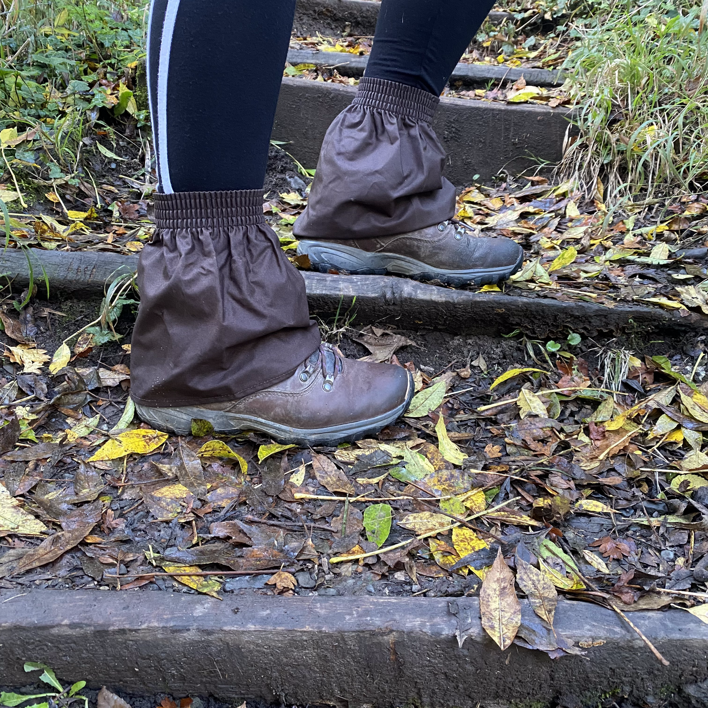 Person wearing brown ankle covers walking on a leaf-covered path