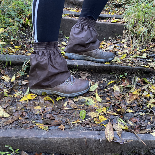Person wearing brown ankle covers walking on a leaf-covered path