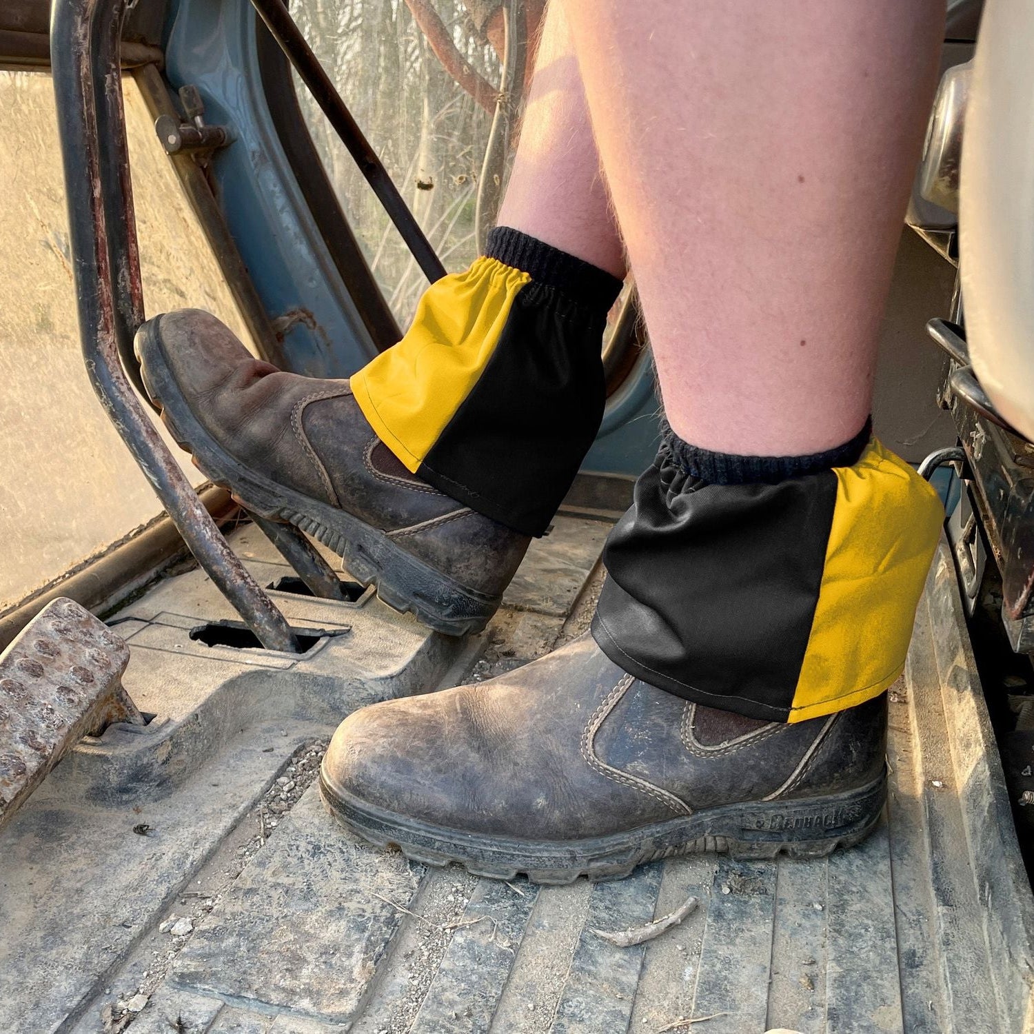 Person wearing yellow and black boot covers on a construction site.
