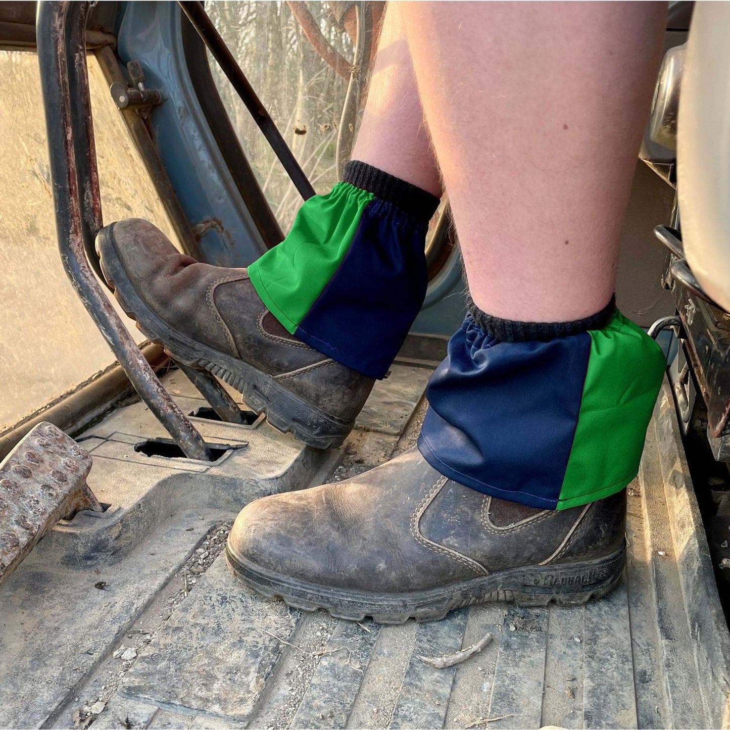 Person wearing green and blue gaiters on boots in a construction setting
