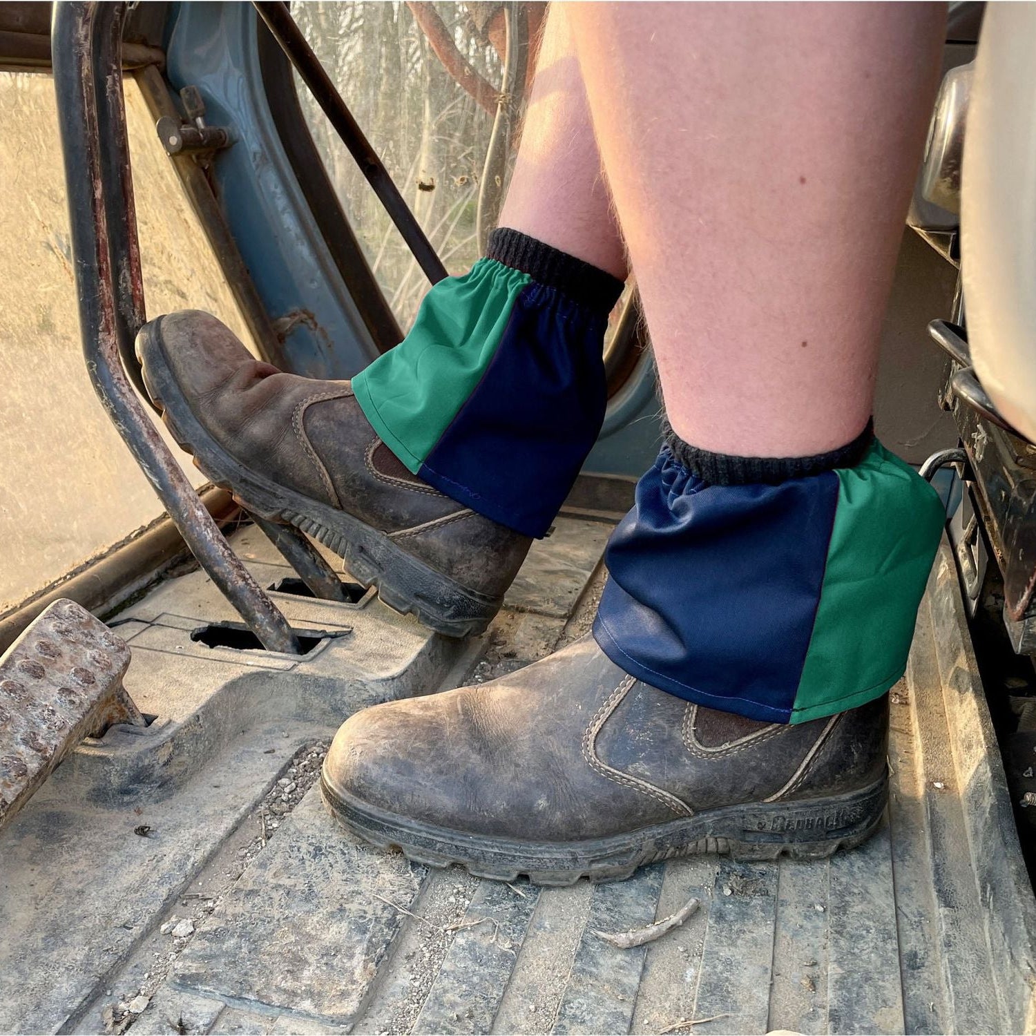 Person wearing green and blue gaiters on a construction site