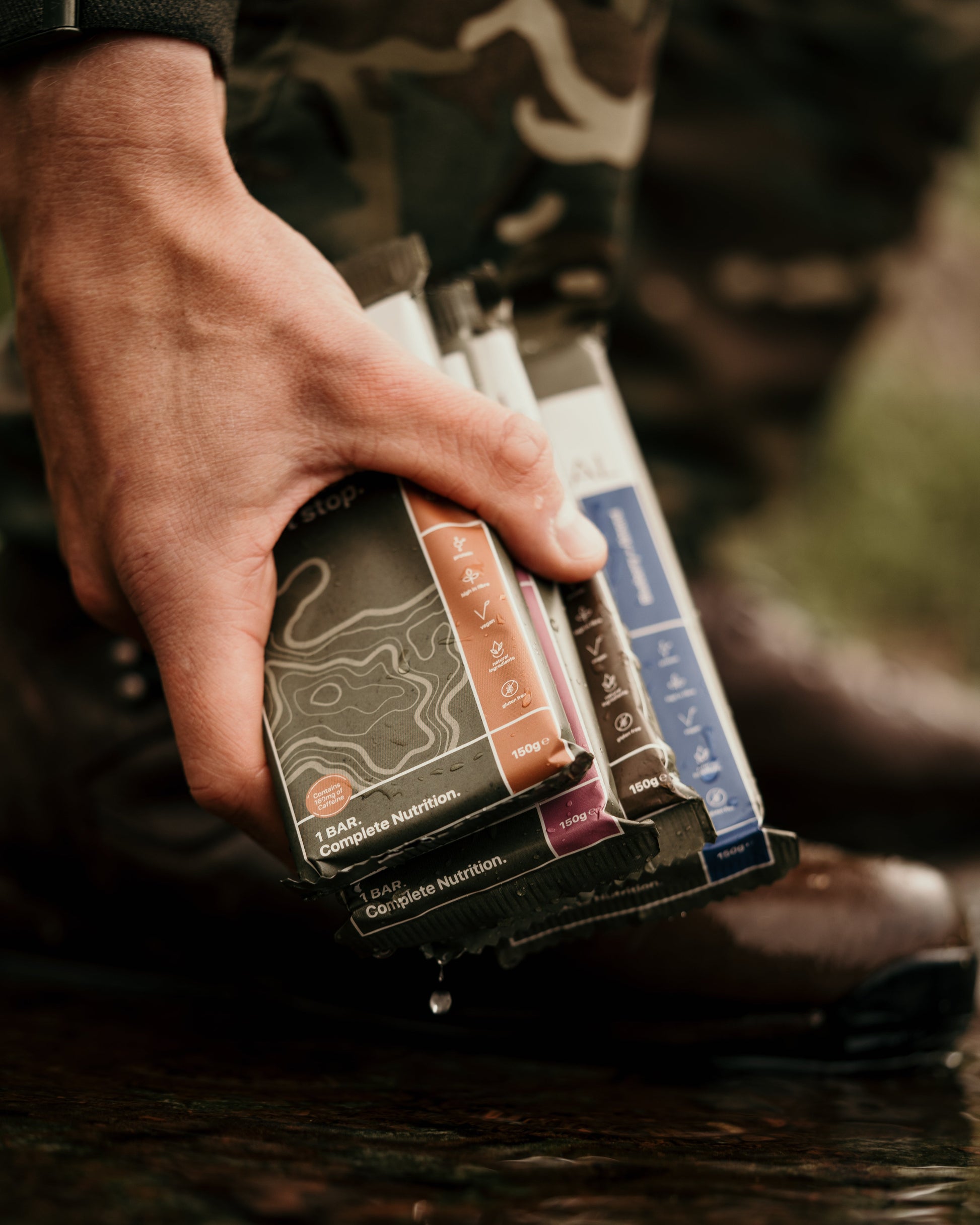 Hand holding a package of hunting ammunition with camouflage background