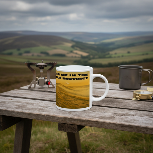 White ceramic mug with yellow and black "I'd Rather Be in the Peak District" text on a wooden picnic table outdoors.