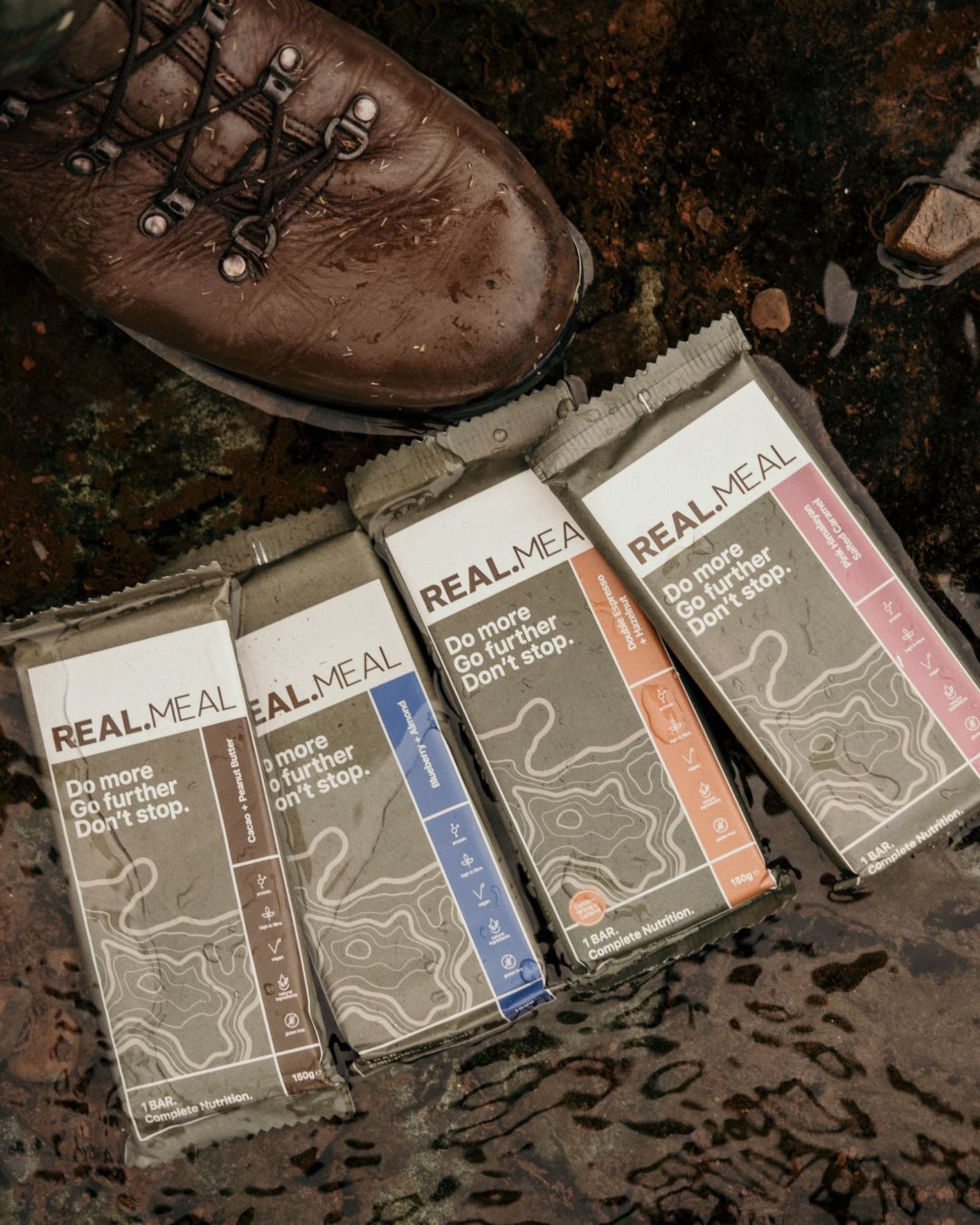 Real Meal packages on a textured surface with a boot in the background