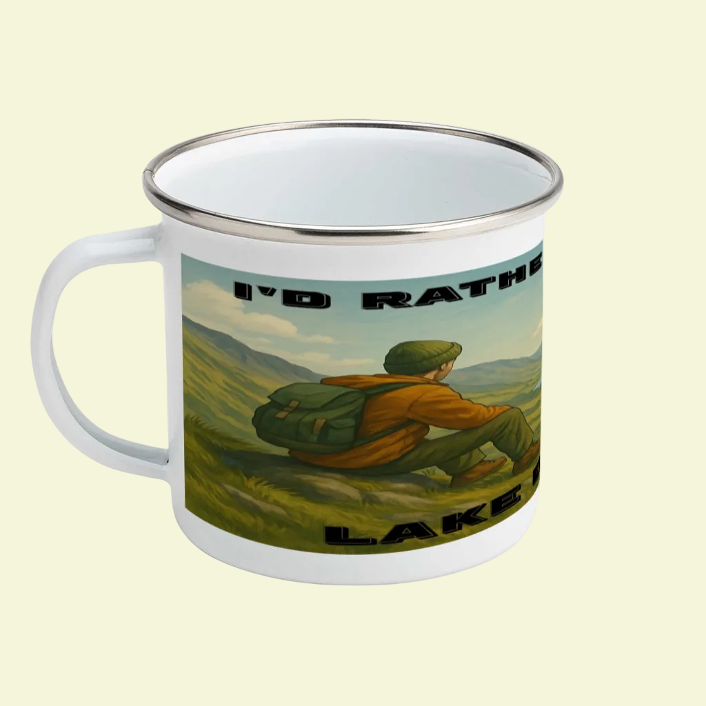 White enamel mug with silver rim featuring a hiker overlooking green hills and "I'd Rather Be in the Lake District" text.